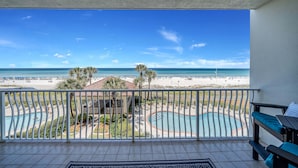 A balcony with a view of a beach, a pool, and lounge chairs. - Beachfront 2br/2ba condo on the 3rd floor with free beach chairs included! (Panama City Beach)