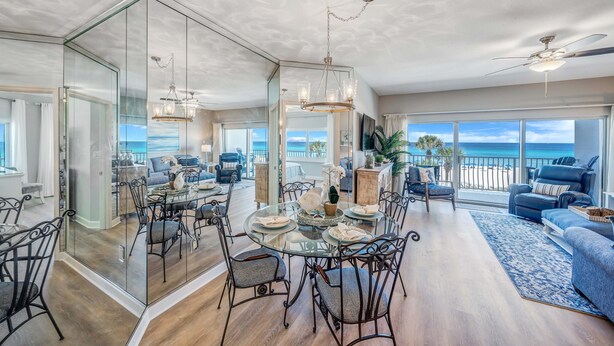 A spacious dining area with a glass table and chairs, a chandelier, and a view of the ocean. - Beachfront 2br/2ba condo on the 3rd floor with free beach chairs included! (Panama City Beach)