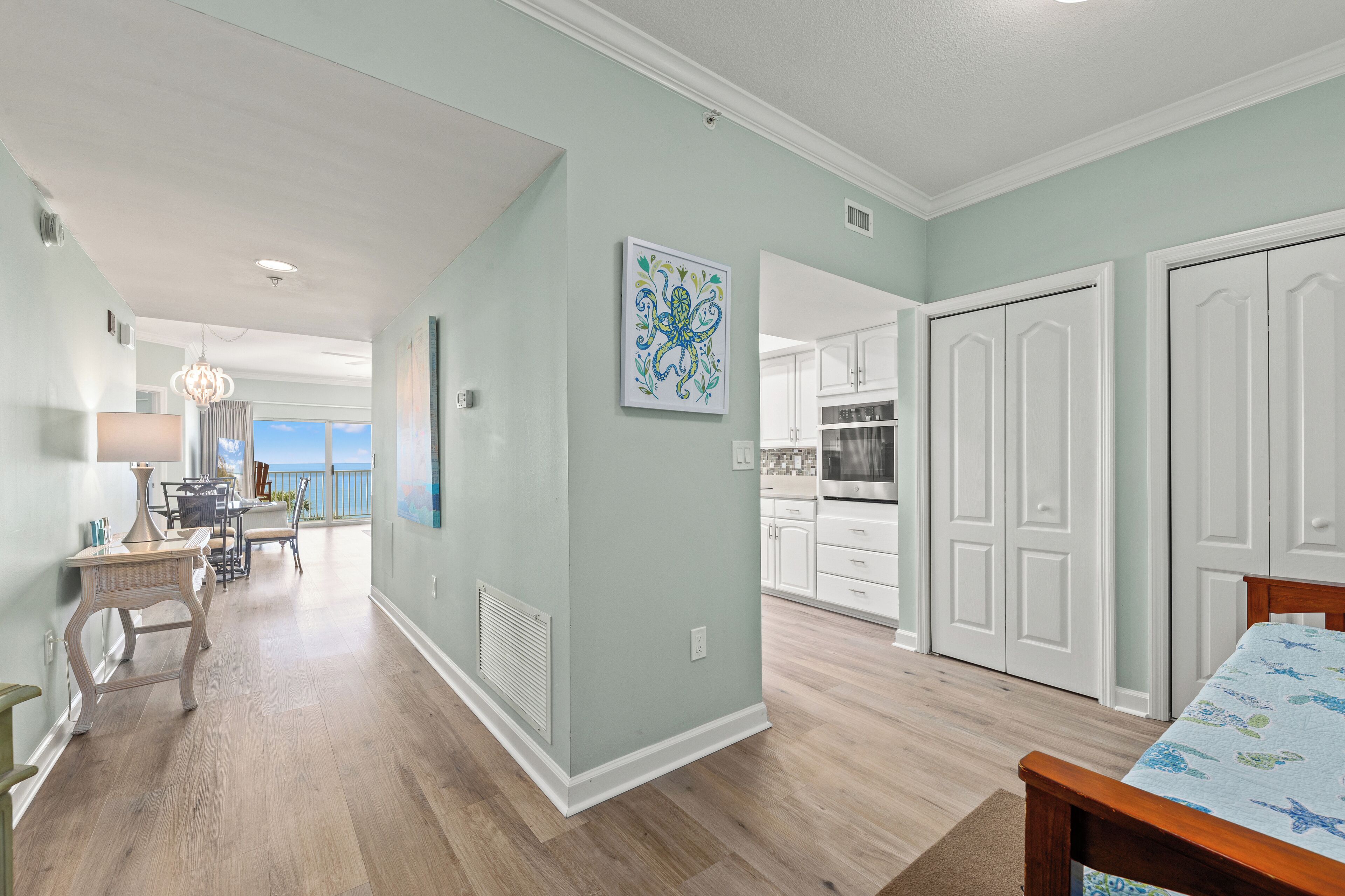 A spacious living area with a dining table, a kitchen with white cabinets, and a large window overlooking a balcony.