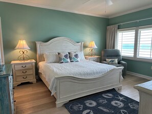 Une chambre à coucher avec un lit, des tables de chevet, une chaise et une fenêtre avec des rideaux.