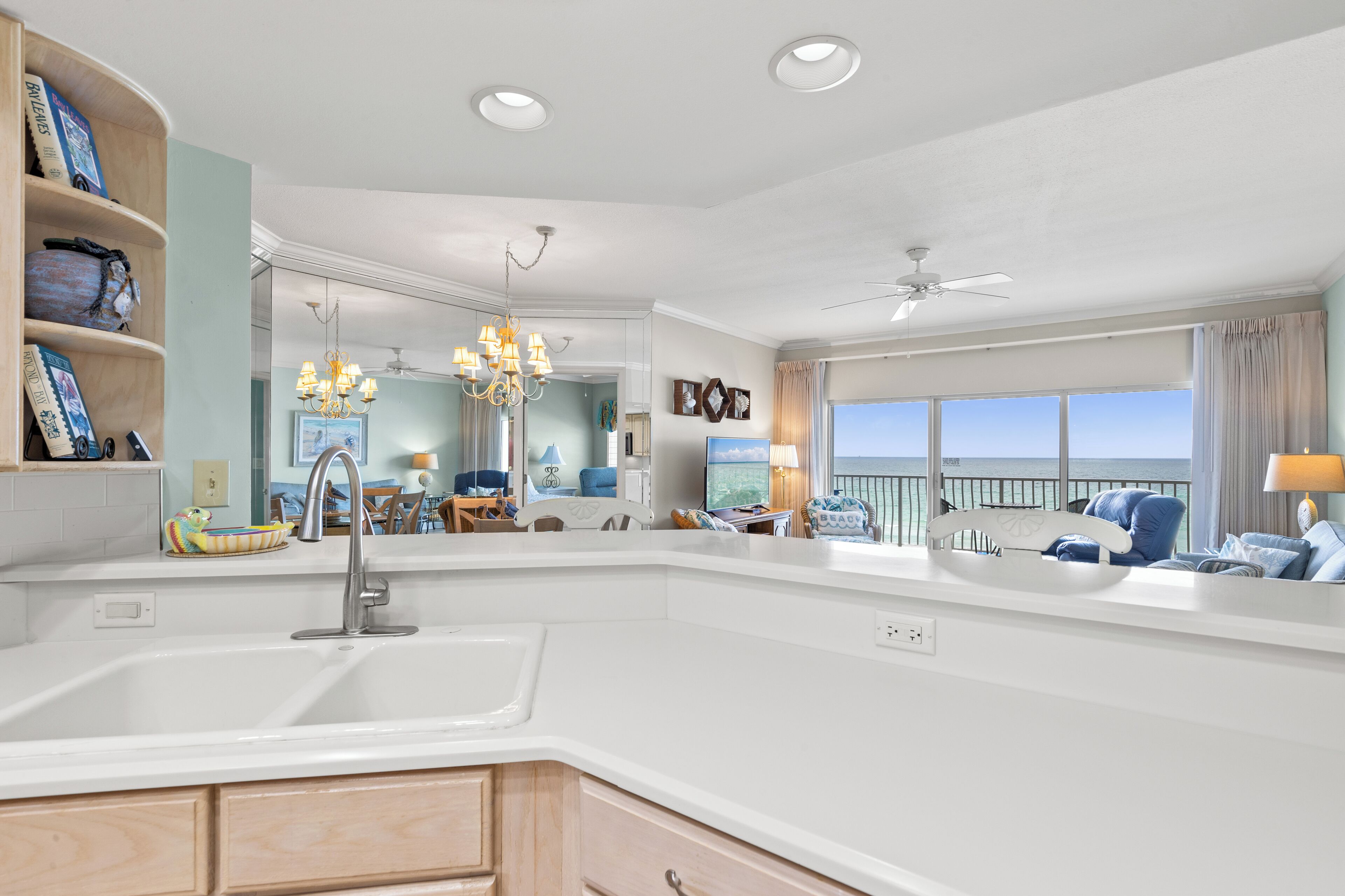A modern kitchen with a large island, a dining area with a chandelier, and a view of the ocean.