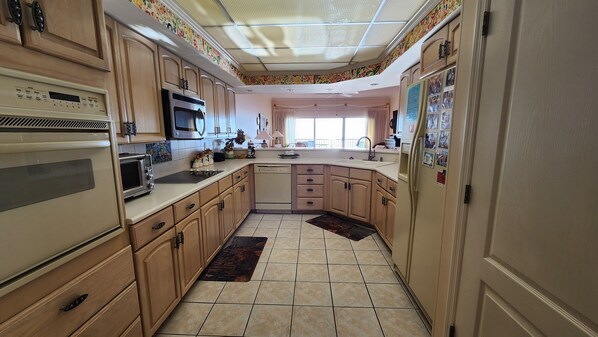 A kitchen with wooden cabinets, a microwave, an oven, a dishwasher, and a refrigerator. - Coral Reef Unit#505 (Beachfront 2 bedroom 2 bath condo on the 5th floor) (Panama City Beach)