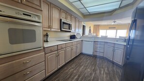 Una cocina moderna con armarios de madera, microondas, lavavajillas y refrigerador.
