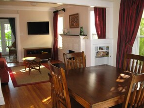 Un comedor con una mesa y sillas de madera, un televisor montado en la pared y una chimenea con repisa.