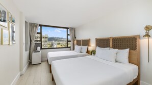 A hotel room with two beds, a large window with a view of buildings and mountains, and a wall-mounted air conditioner. - Waikiki Golden Gem: 1 Br w/ Free Parking (Honolulu)