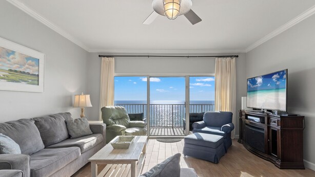 A living room with a sofa, armchairs, a coffee table, a TV, and a view of the ocean through large windows. - Coral Reef Unit#706 (Beachfront 4 bedroom 3 bath condo on the 7th floor) (Panama City Beach)