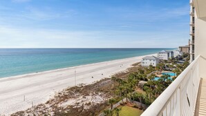A beach view from a balcony overlooking a sandy beach and ocean.