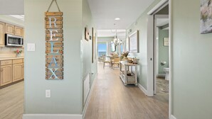 A hallway with a wooden sign reading "RELAX" and a view into a dining area with a chandelier.