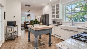 Una cucina moderna con mobili bianchi, un piano di lavoro in marmo e un'ampia finestra che si affaccia sul verde.