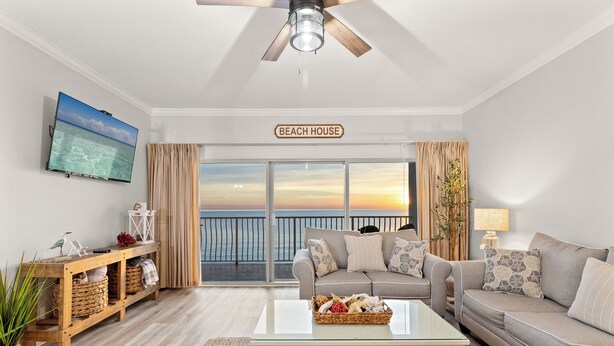 En stue med en sofa, et sofabord, et fjernsyn og et skilt der står "BEACH HOUSE".