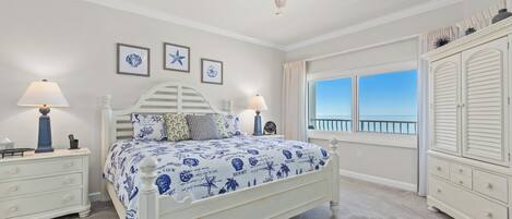 Un dormitorio con cama, mesitas de noche, cómoda, ventilador de techo y ventana con vistas.