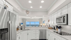 A modern kitchen with white cabinetry, stainless steel appliances, a dishwasher, and a large window offering a view of the ocean. - Coral Reef, Unit #1102 (Beachfront 2 bedroom 2 bath condo on the 11th floor) (Panama City Beach)