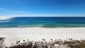 A wide sandy beach with a clear blue ocean and a few scattered structures. - Coral Reef Unit #1405 Beachfront 2 bedroom 2 bath condo on the TOP floor!!! (Panama City Beach)