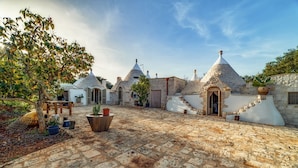 A courtyard with stone buildings, a tree, and potted plants.