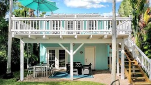 A covered outdoor seating area with a patio table and chairs, a small pool, and a staircase leading to a second level.