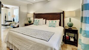 A neatly arranged bedroom with a large bed, two bedside tables with lamps, a dresser, and a mirror.