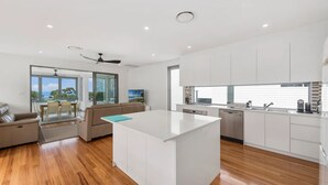 A modern kitchen with white cabinetry, a central island, and a dining area with a sofa and table. - Pearls on Sapphire Beach (Sapphire Beach)
