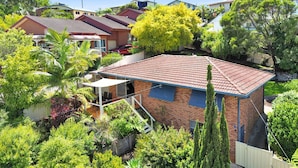 Ein Wohnhaus mit rotem Ziegeldach, Ziegelaußenwand und einer kleinen Terrasse mit Gartenmöbeln.