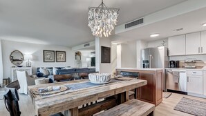 A modern kitchen with white cabinetry, a stainless steel refrigerator, and a wooden dining table with benches.