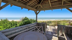 A wooden deck with a view of the beach and ocean.