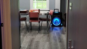 Un pasillo con zona de comedor, un ventanal grande y un dispositivo iluminado en azul.