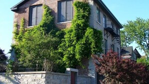 Une maison à deux étages avec une façade en briques et de grandes fenêtres.