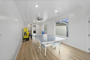 Una mesa de ping pong en una habitación con paredes blancas y suelo de madera.
