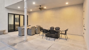 An outdoor patio with a dining table and chairs, a ceiling fan, and a concrete floor. - Brand New Home! Roof Top Deck, Games for everyone, Private Pool (Hurricane)