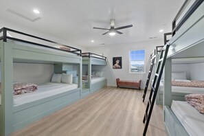 Dormitorio con literas, ventilador de techo, ventana y banco.