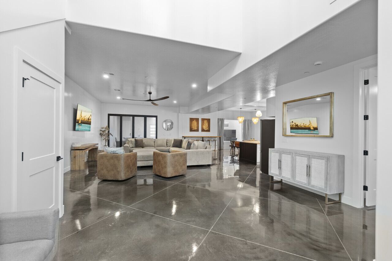 A spacious living area with a modern design, featuring a large sofa set, a coffee table, and a cabinet.