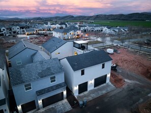 A residential area with modern houses, a clear sky, and distant mountains. - Brand New Home! Roof Top Deck, Games for everyone, Private Pool (Hurricane)