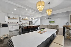 A modern kitchen with white cabinetry, a large island, and pendant lighting. - Brand New Home! Roof Top Deck, Games for everyone, Private Pool (Hurricane)