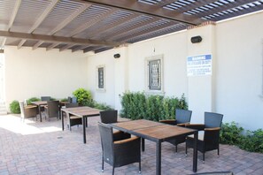 An outdoor patio with tables and chairs, a covered area, and a warning sign on the wall. - Brand New Home! Roof Top Deck, Games for everyone, Private Pool (Hurricane)