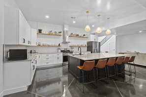 A modern kitchen with white cabinetry, a central island with bar stools, and pendant lighting.