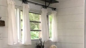 A kitchen with white paneled walls, a black countertop, and a bench with black and white stripes. - LINVILLE Nostalgic Mountain Farm Glamping Camper on Wedding Venue, 10 acre farm  (Linville)