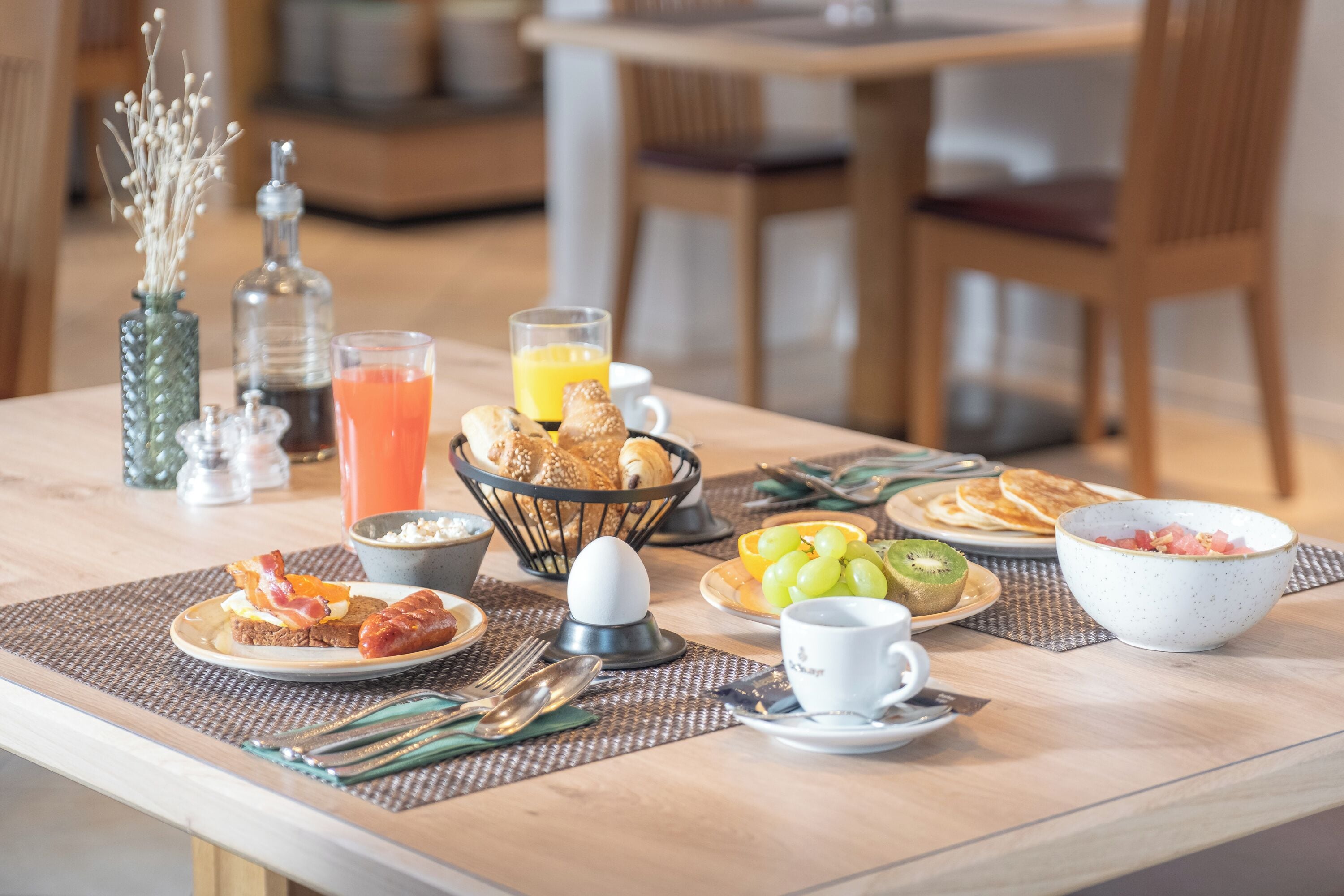 Ein Frühstückstisch mit verschiedenen Frühstücksangeboten, darunter Eier, Toast, Obst und Getränke.