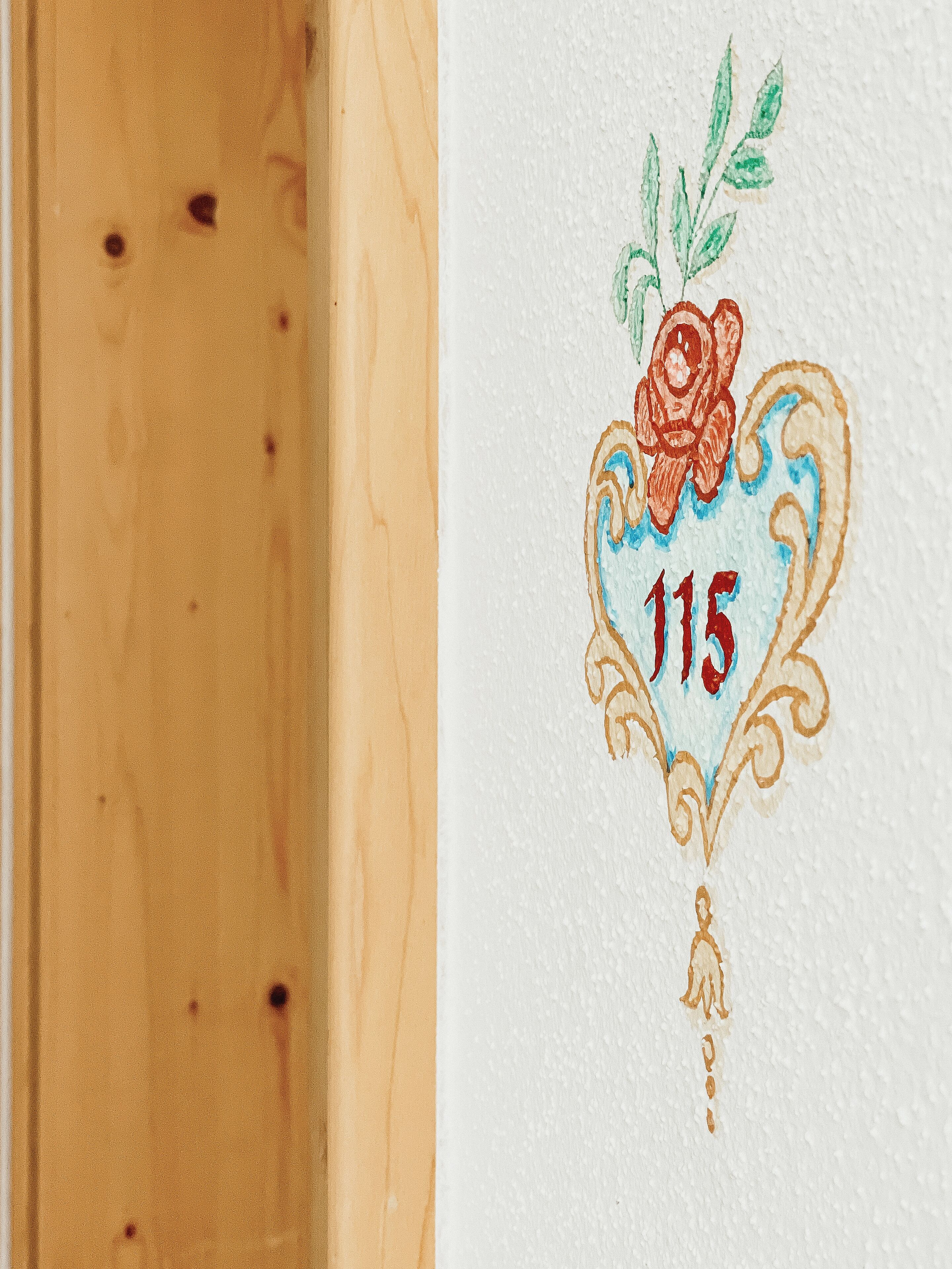 Un mur orné d’un motif décoratif représentant une rose et le chiffre 115.