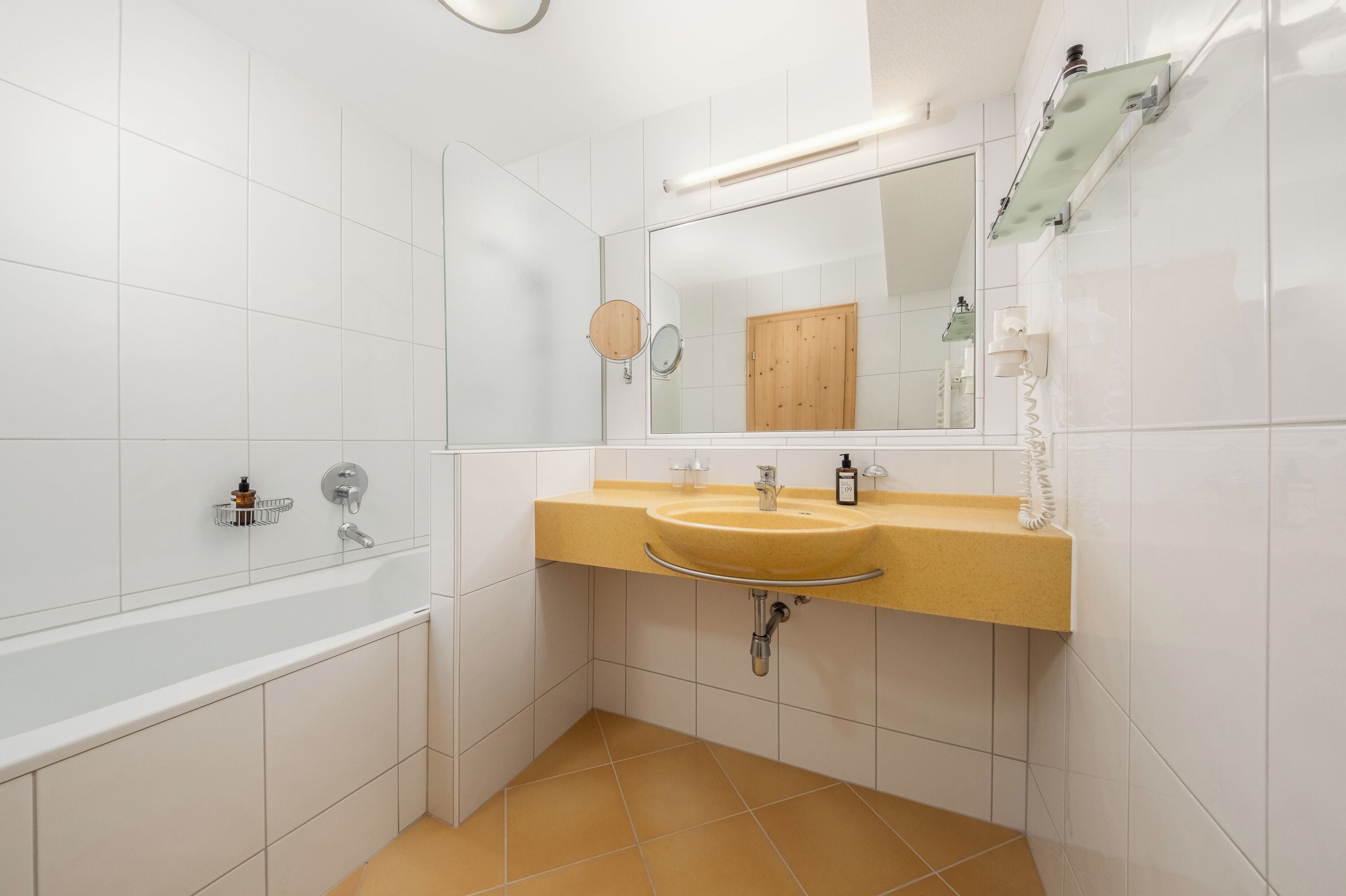 Een moderne badkamer met een bad, twee wastafels en een grote spiegel.