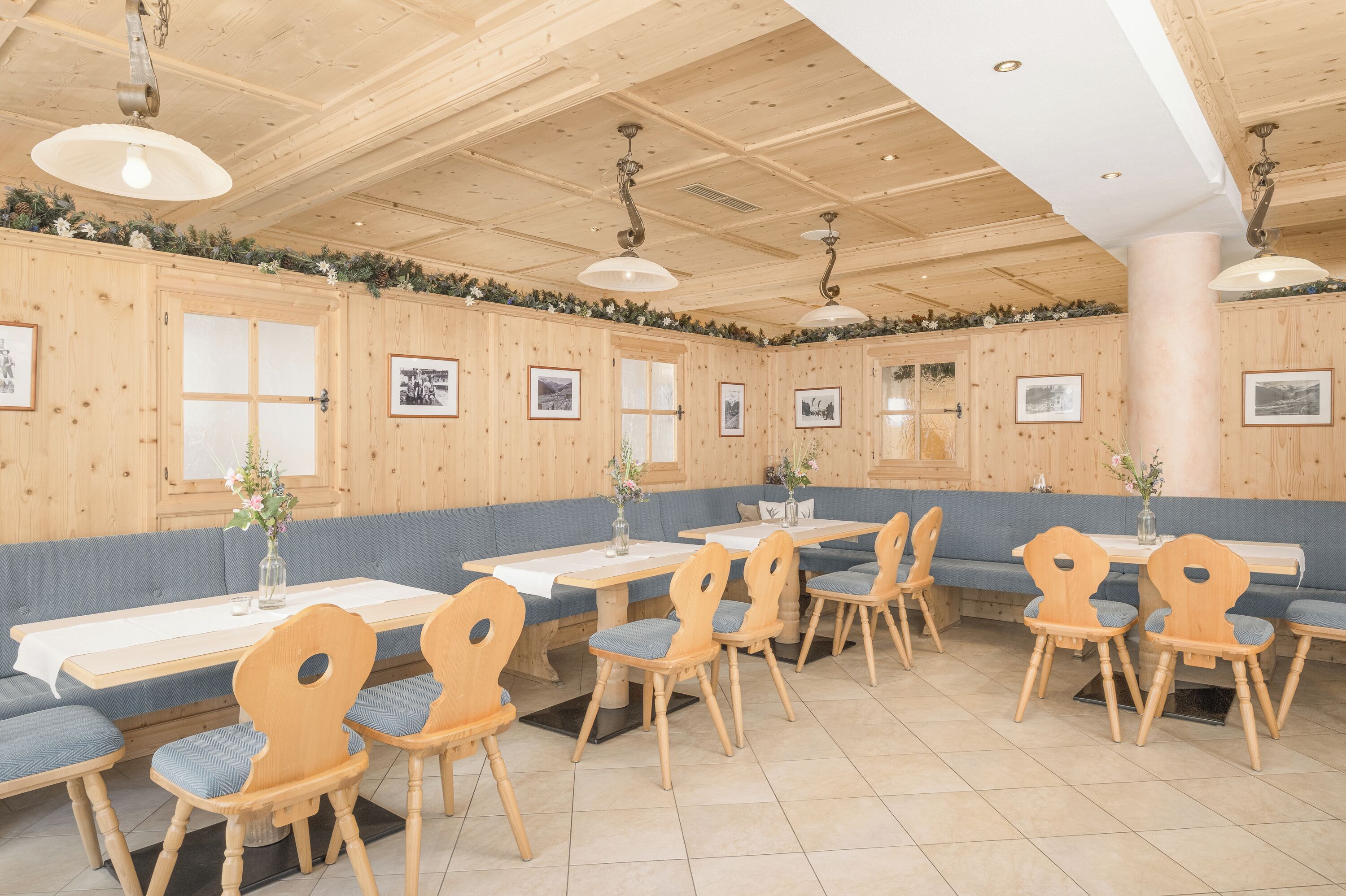 A restaurant with wooden walls, blue cushioned benches, and wooden tables with chairs.