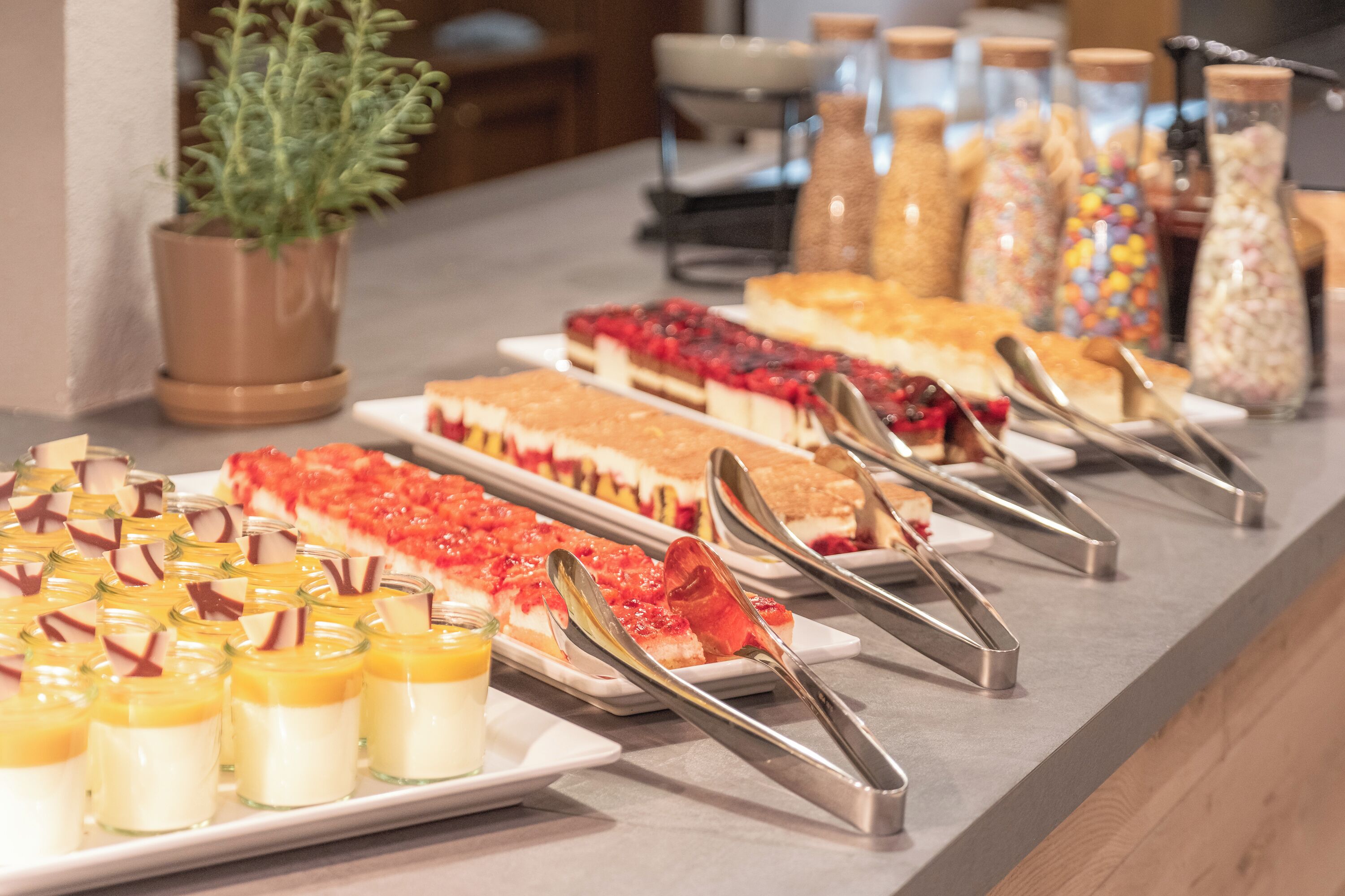A buffet with various desserts and a potted plant.