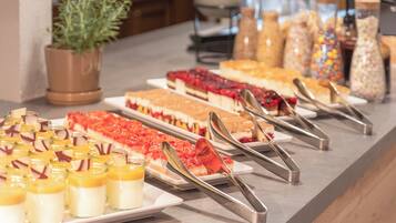 A buffet with various desserts and a potted plant.