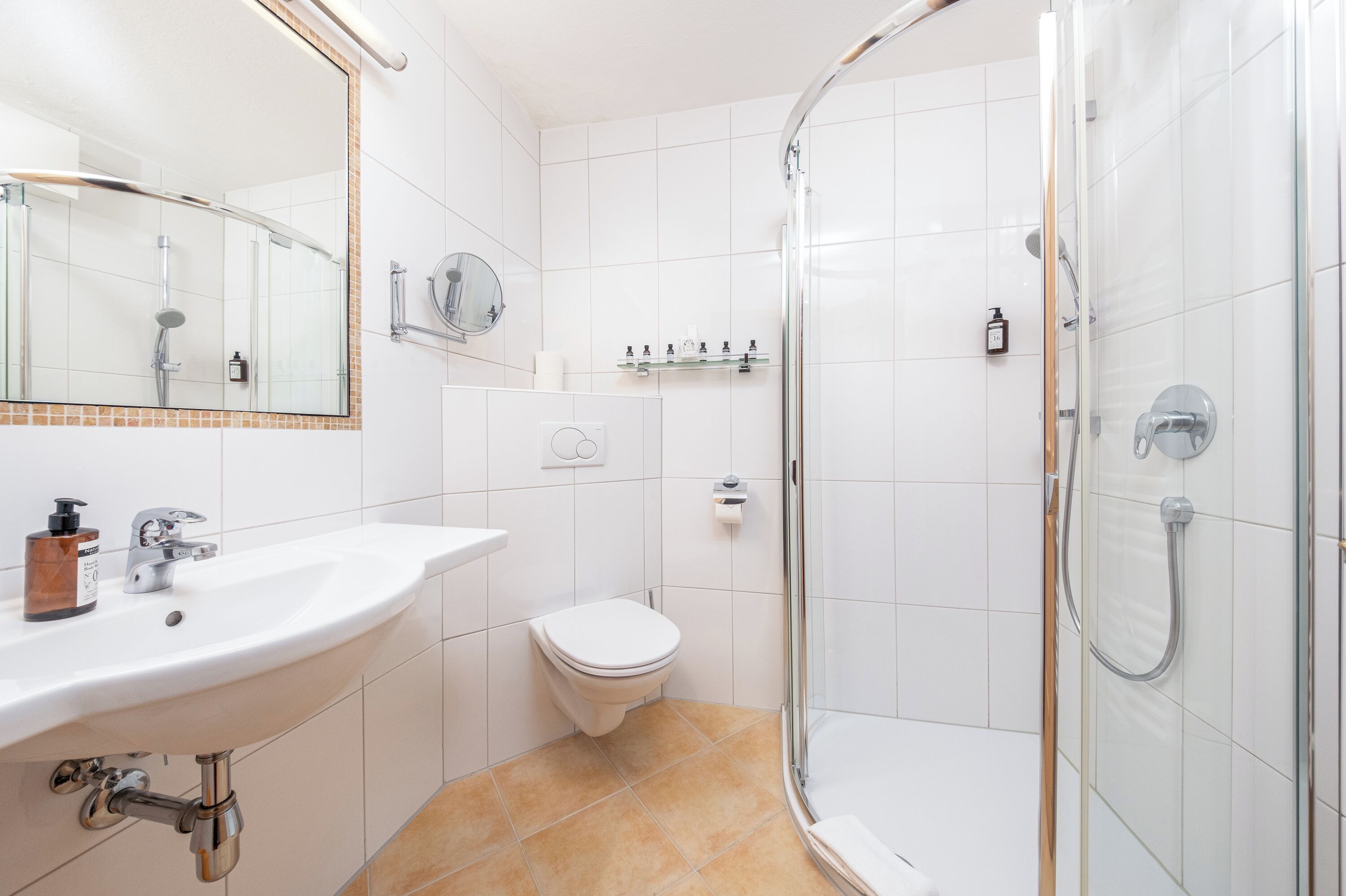 Un baño moderno con lavabo, inodoro y ducha con mampara de vidrio.