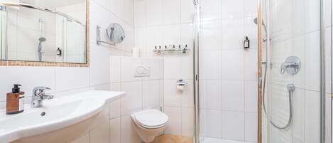 Un baño moderno con lavabo, inodoro y ducha con mampara de vidrio.