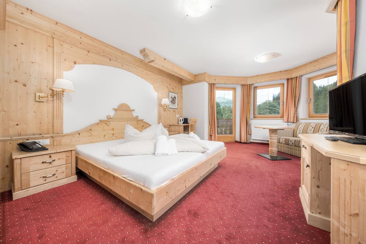 A wooden room with a bed, a desk, and a TV.