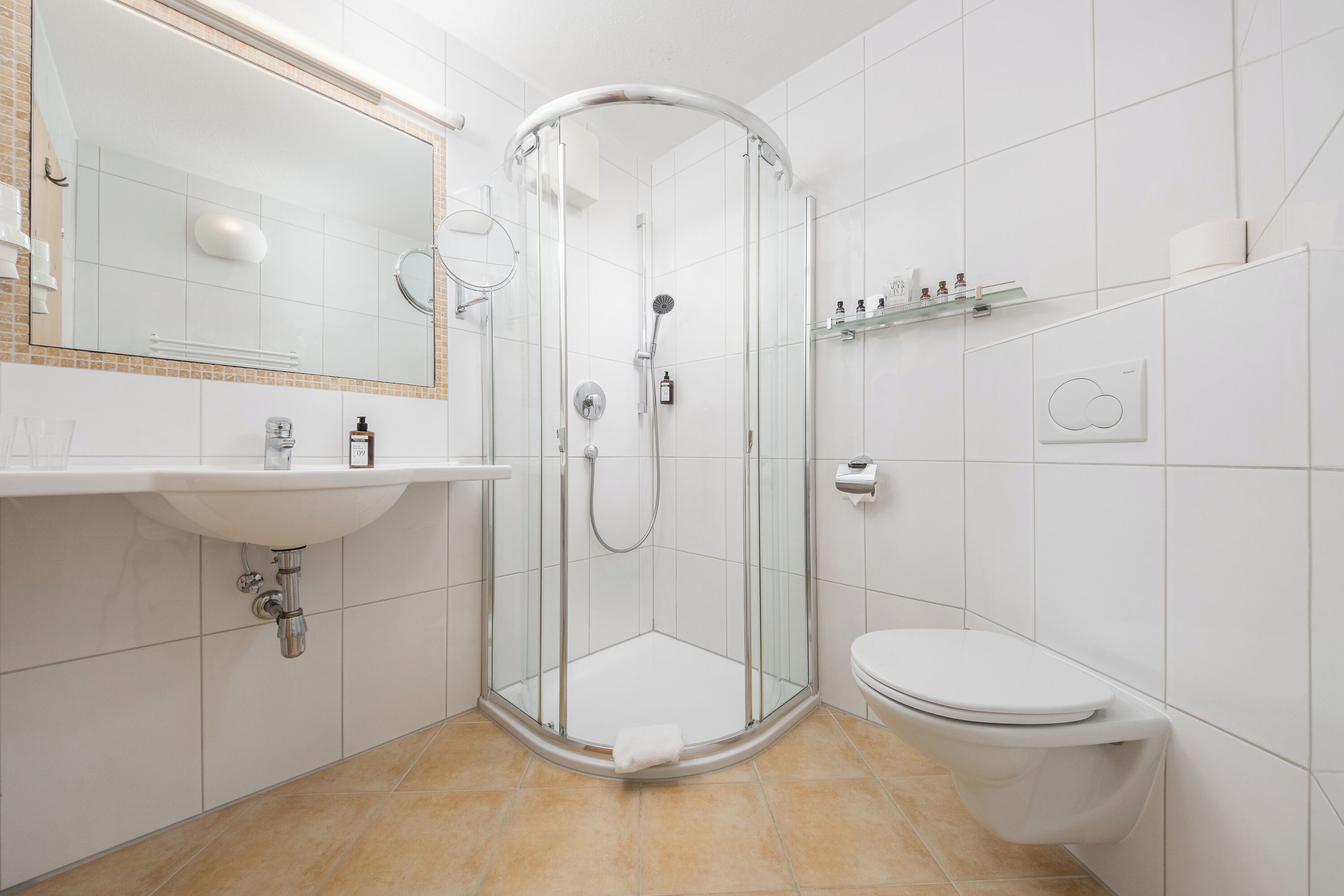 A modern bathroom with a glass-enclosed shower, a white sink, and a toilet.
