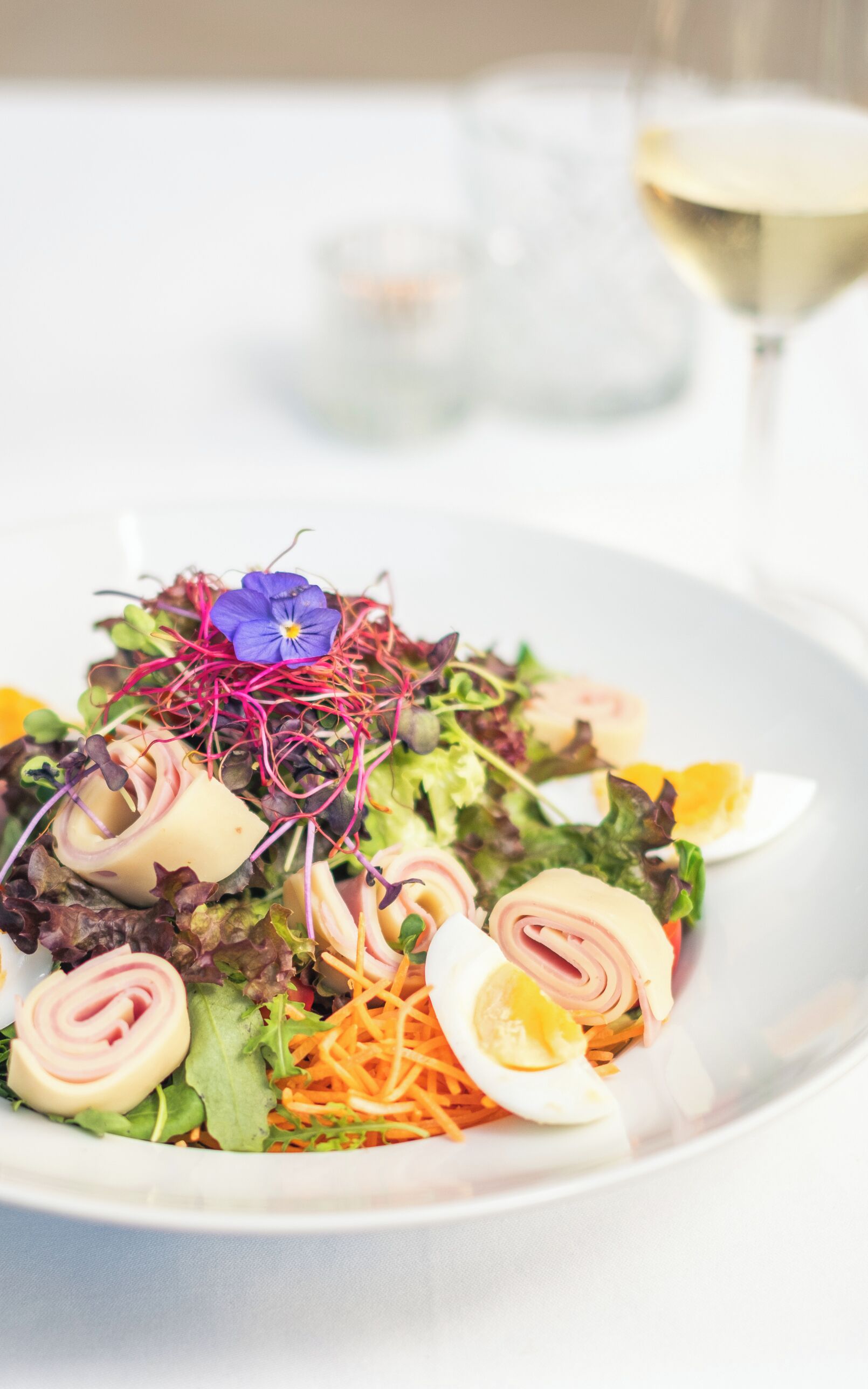 A plate of food with various ingredients including greens, carrots, and a boiled egg.