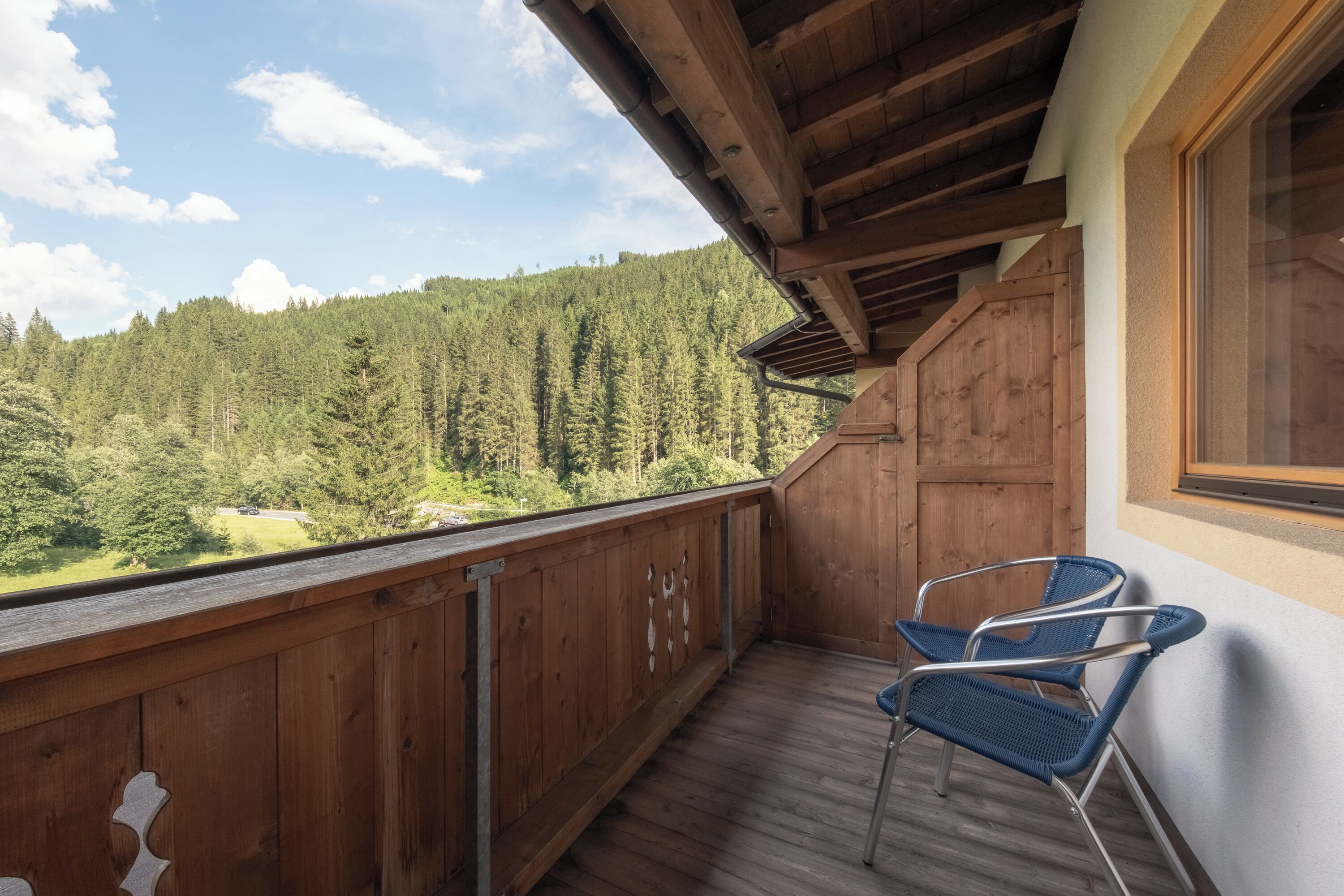 A wooden balcony with a view of a forested area.