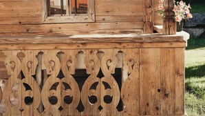 A wooden cabin with a window, a decorative wooden panel, and a small porch area. - Alpenhotel Tirolerhof (Gerlos)