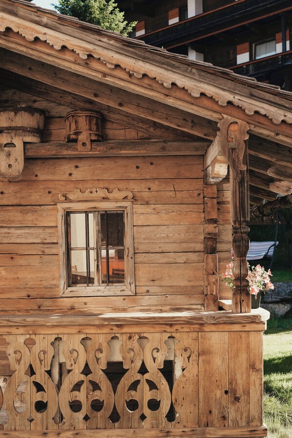 A wooden cabin with a window, a decorative wooden panel, and a small porch area.