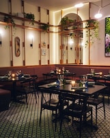 Un restaurante con mesas redondas, sillas y plantas colgantes.